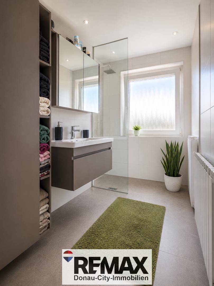 Stilvolles Badezimmer mit schwebendem Waschtisch, Spiegelschrank und großer Dusche.