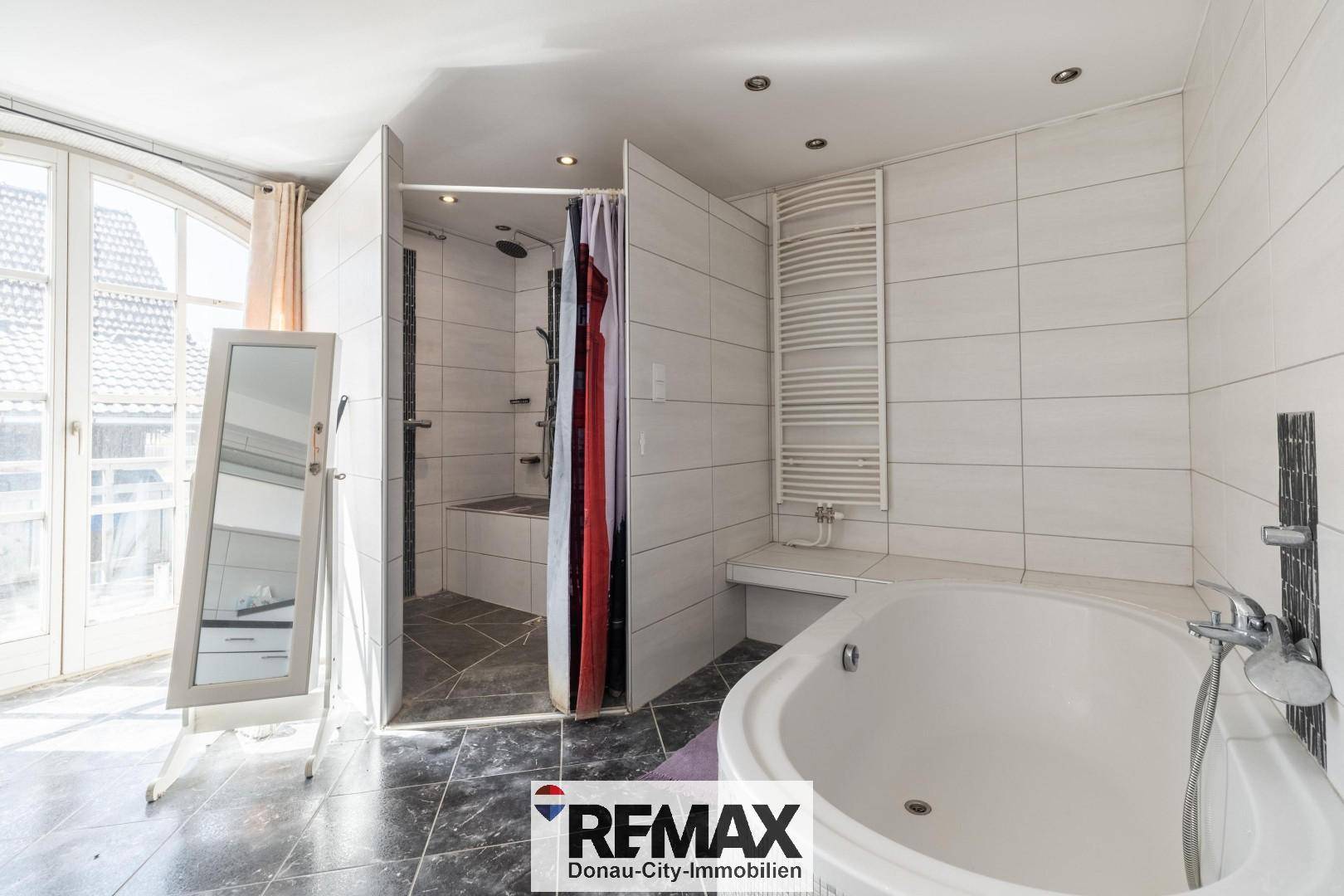 Helles Badezimmer mit Badewanne, Duschkabine und Zugang zu einem Außenbereich.