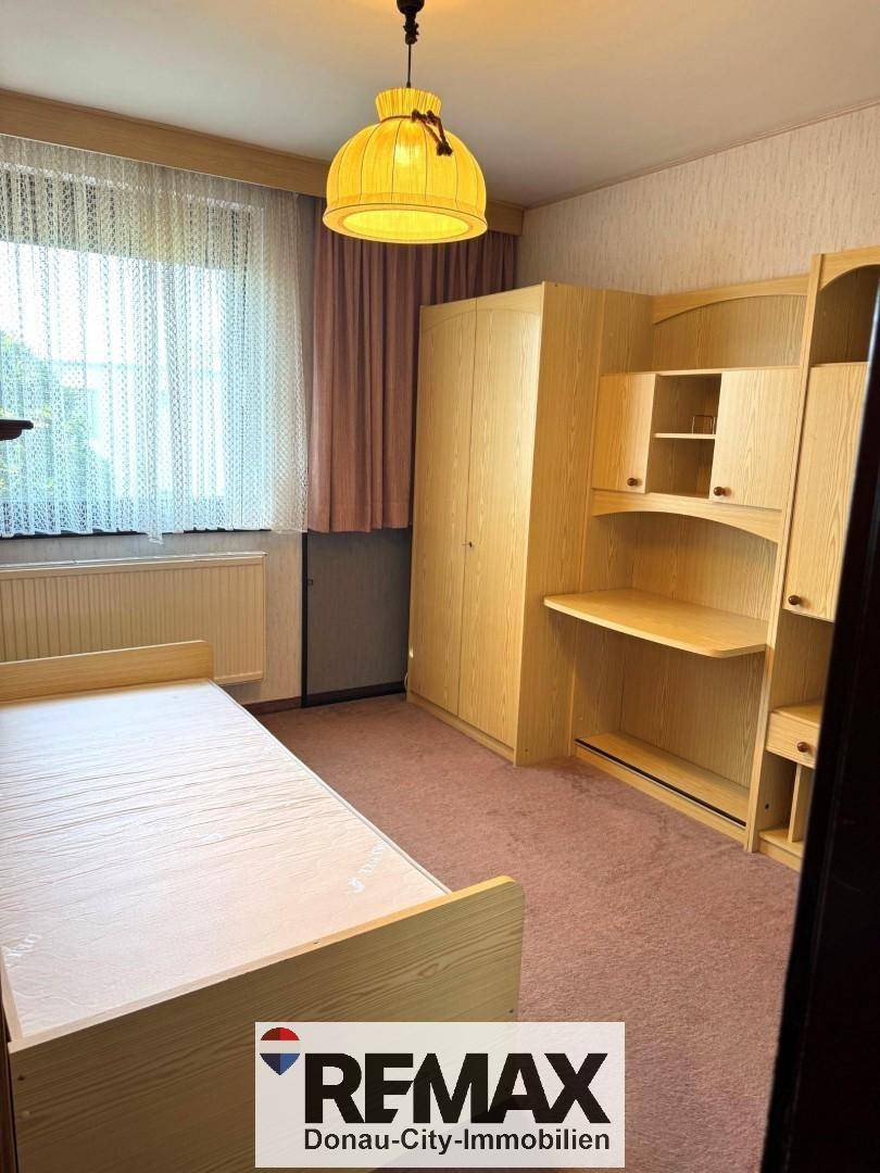 Kinder- oder Gästezimmer mit Einzelbett, Holzschrank und Schreibtisch, ideal für junge Bewohner.