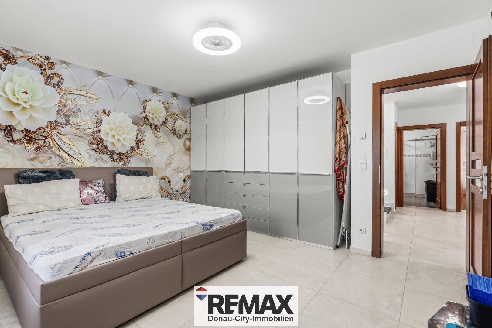 Geräumiges Schlafzimmer mit großem Bett, Einbauschränken und dekorativer Wandtapete.