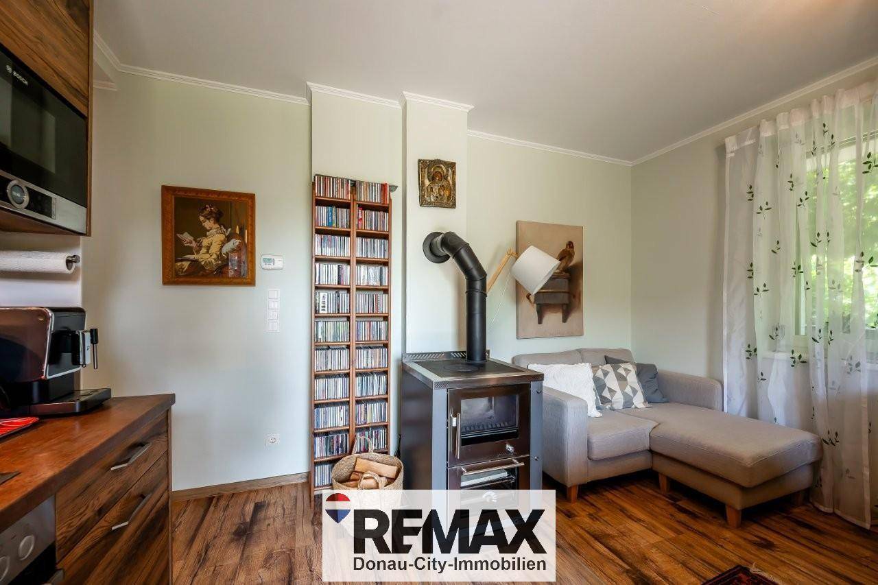 Detailansicht des Wohnbereichs mit gemütlichem Sofa, Bücherregal und traditionellem Holzofen.