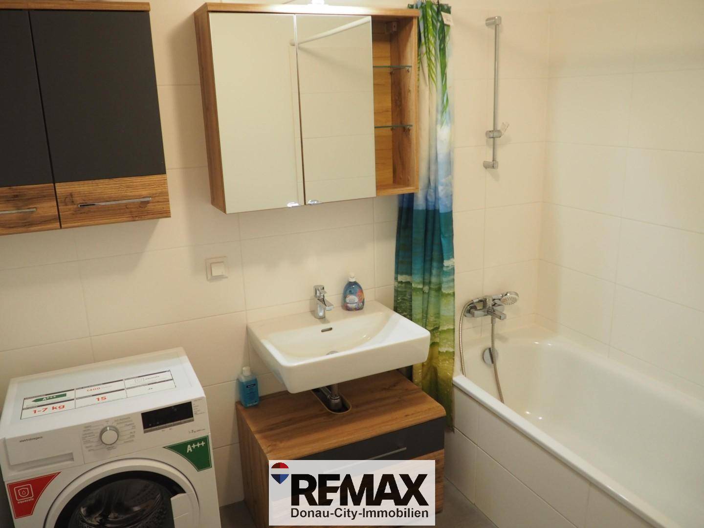 Badezimmer mit Badewanne, Waschbecken und Spiegelschrank, inklusive Waschmaschine.