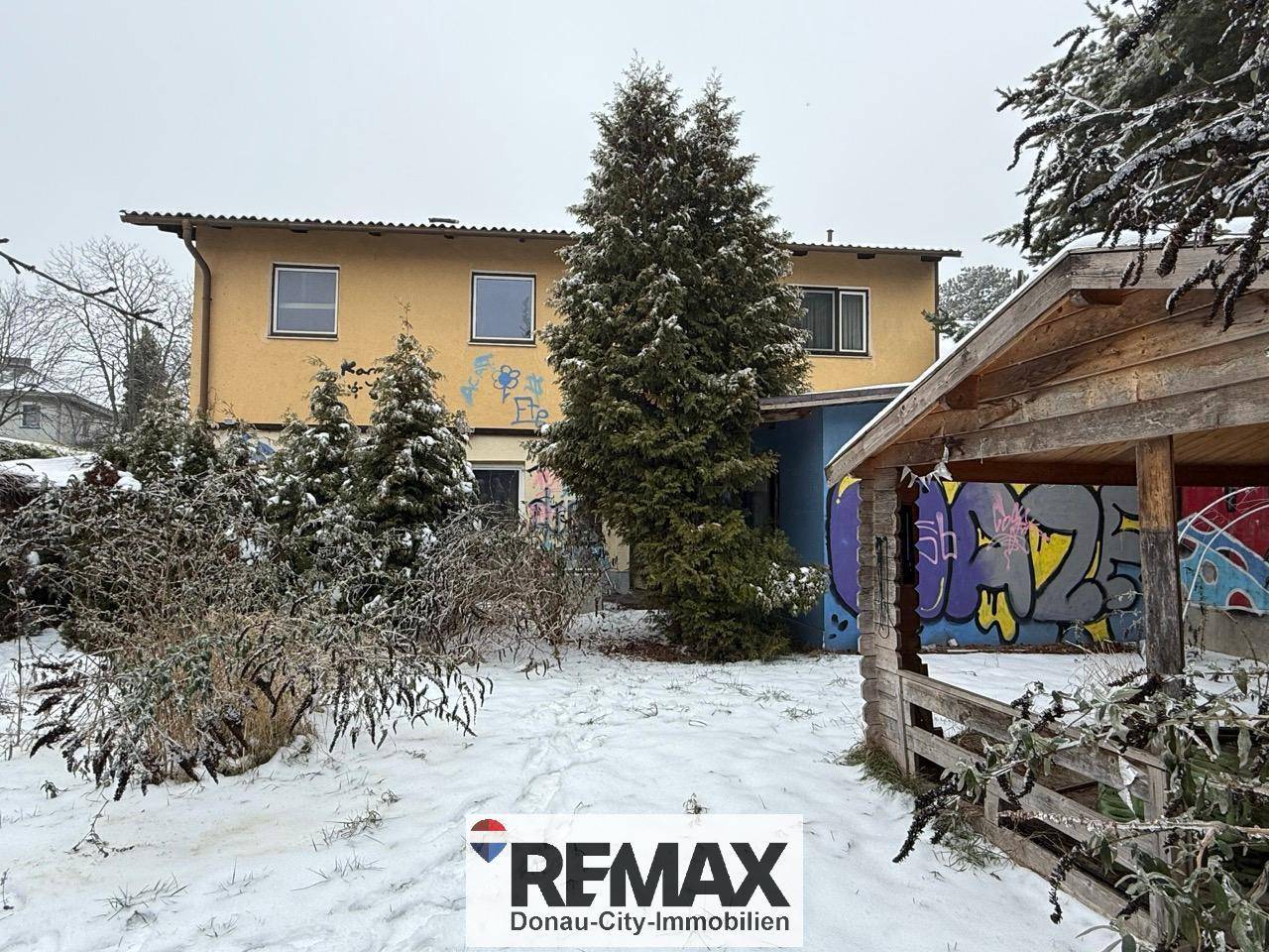 Winterlicher Garten mit Schnee, Bäumen und einem Gartenhaus, das zum Verweilen einlädt.