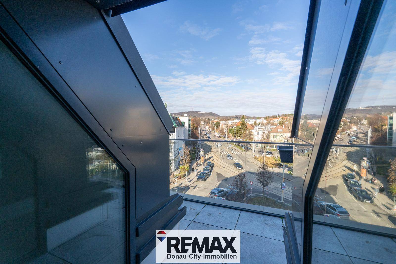 Kleiner Balkon mit Glasbrüstung und weitem Blick über die städtische Umgebung.