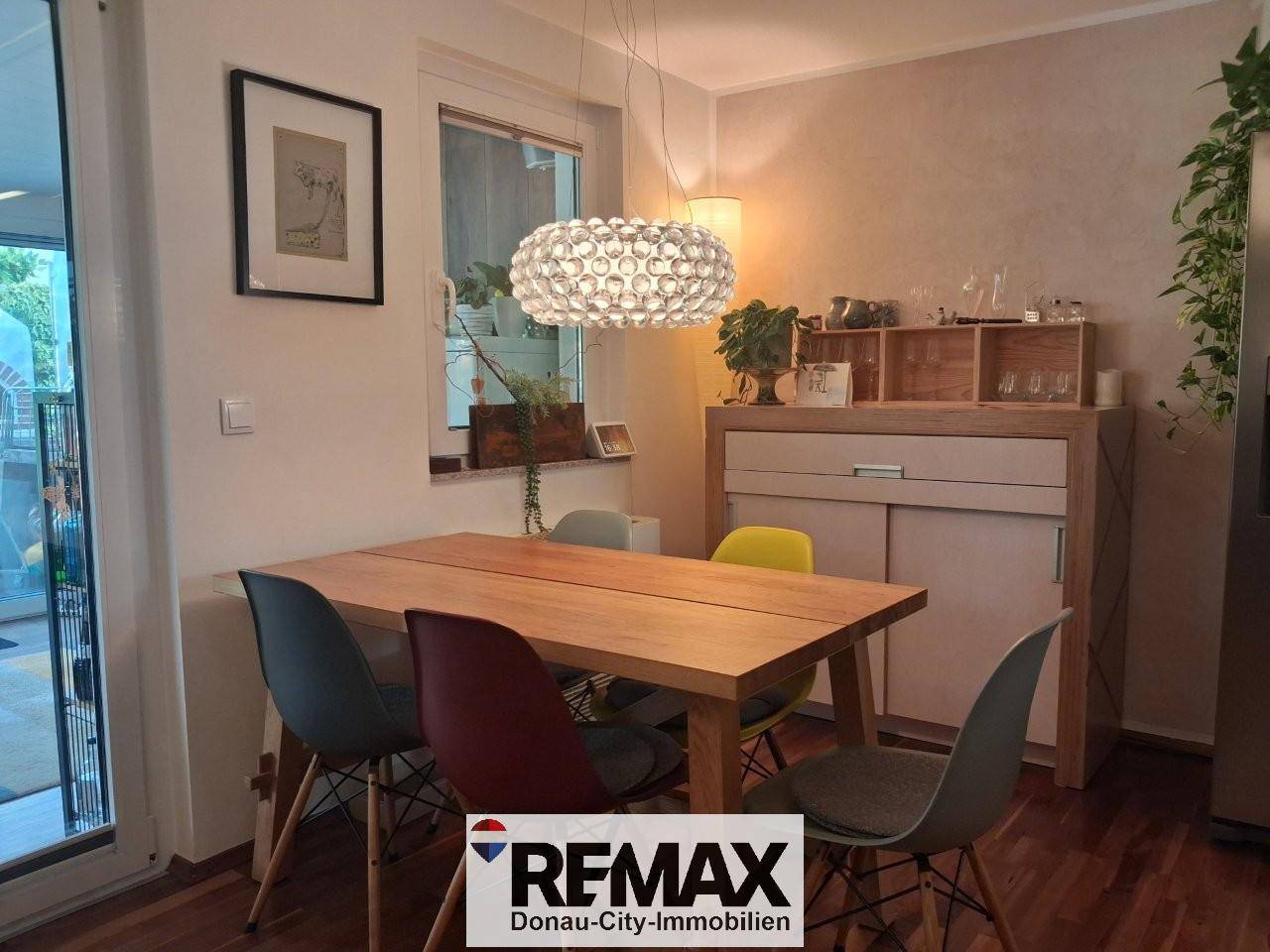 Heller Essbereich mit Holztisch, bunten Stühlen und modernem Deckenlicht.