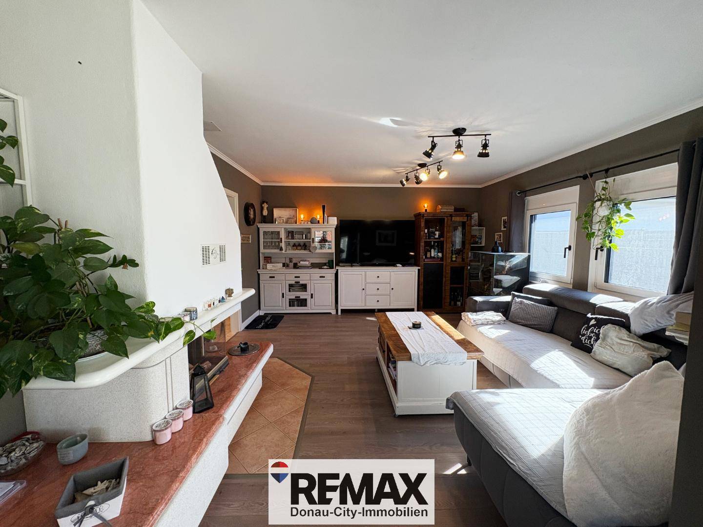 Helles Wohnzimmer mit Kamin, Laminatboden und bequemen Sofas, ideal zum Entspannen.