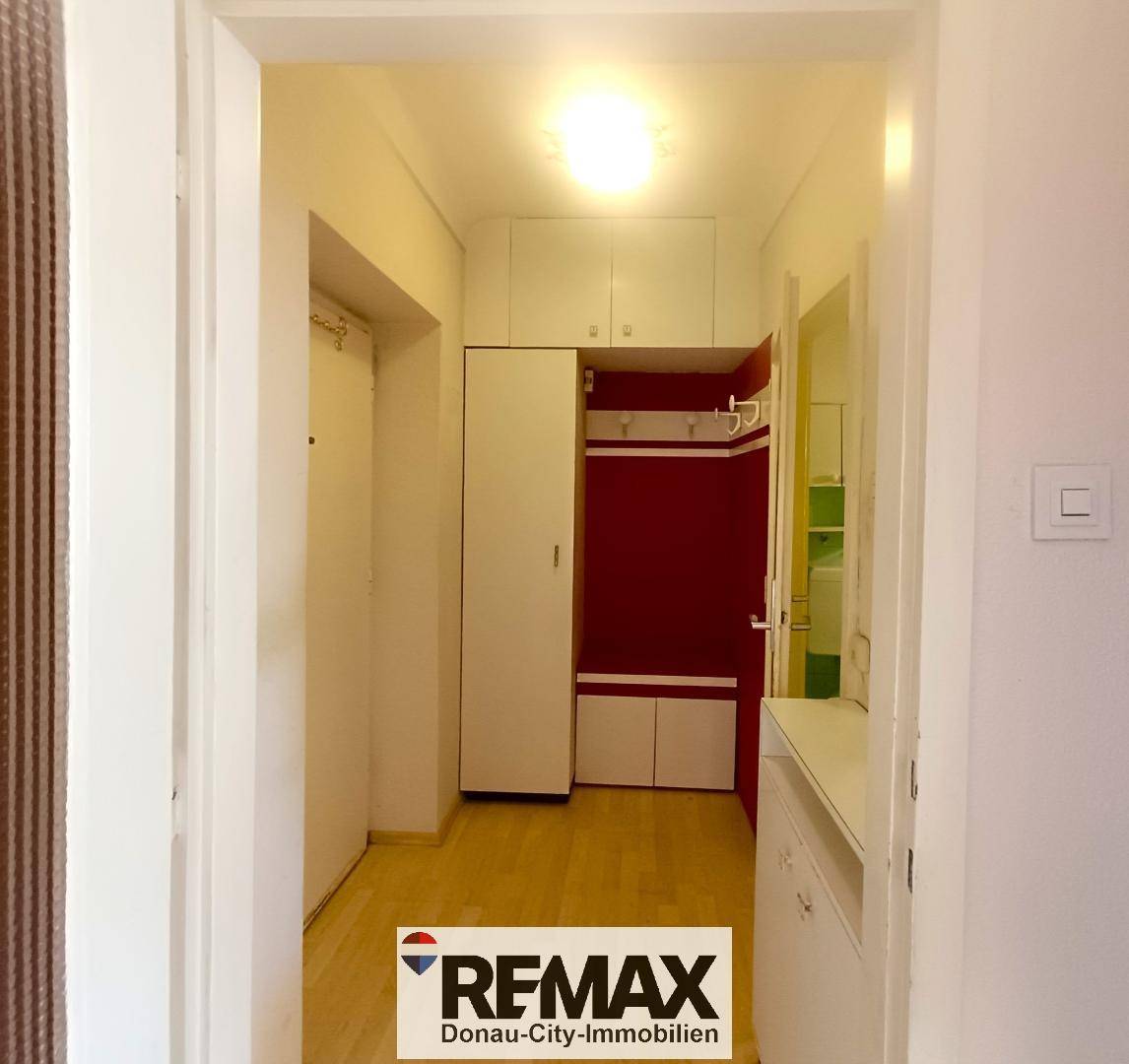 Heller Flur mit weißen Einbauschränken und einer Garderobe.