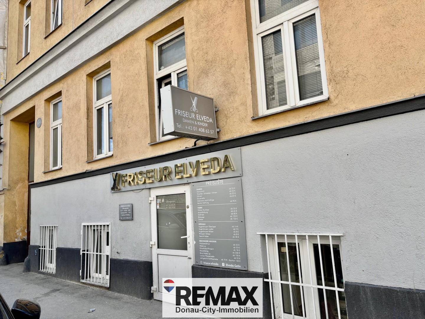Außenansicht des Gebäudes mit dem Eingang zum Friseursalon und großen Fenstern.