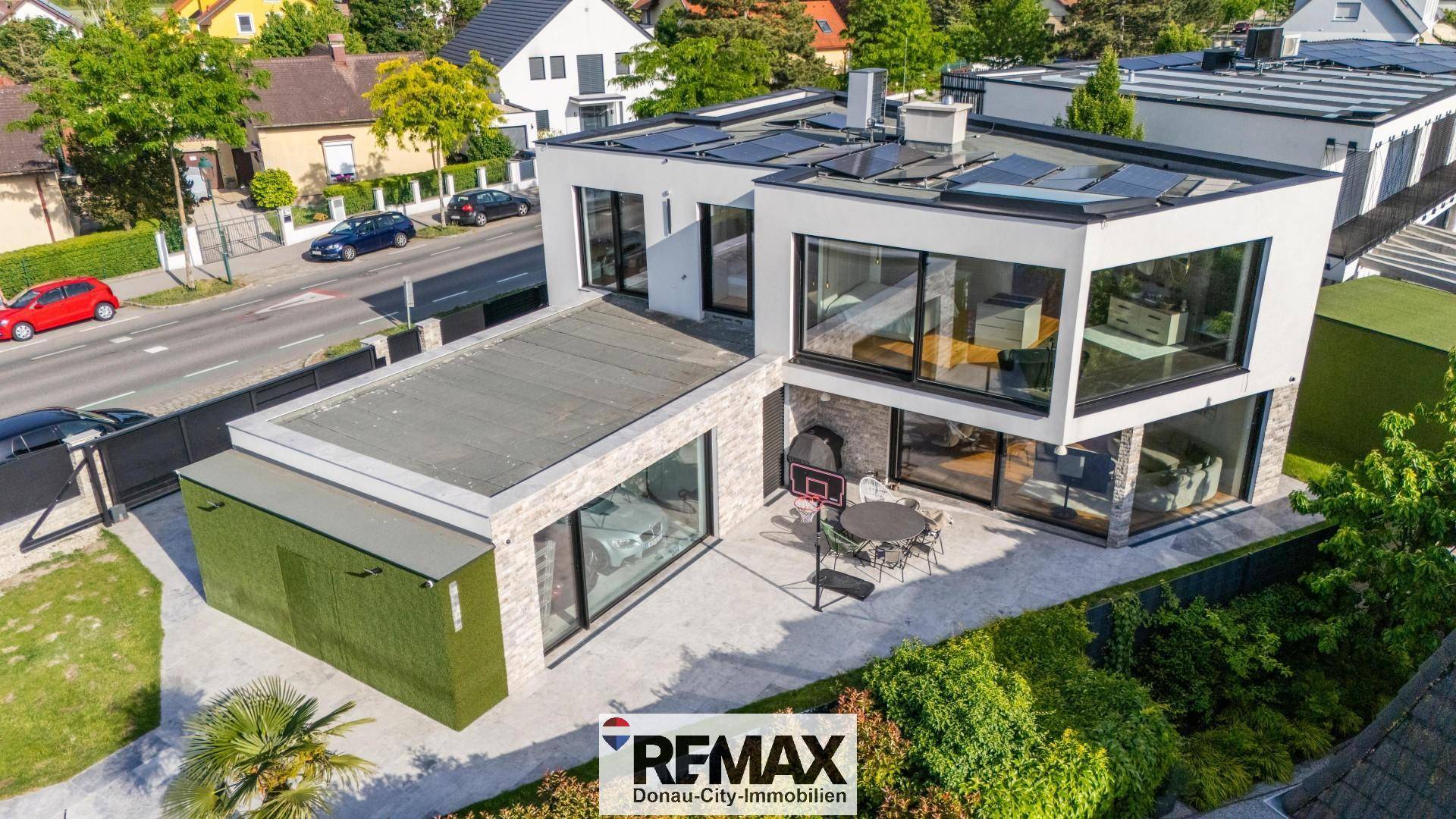Moderne Villa mit großen Glasfronten, Flachdach und gepflegtem Außenbereich.