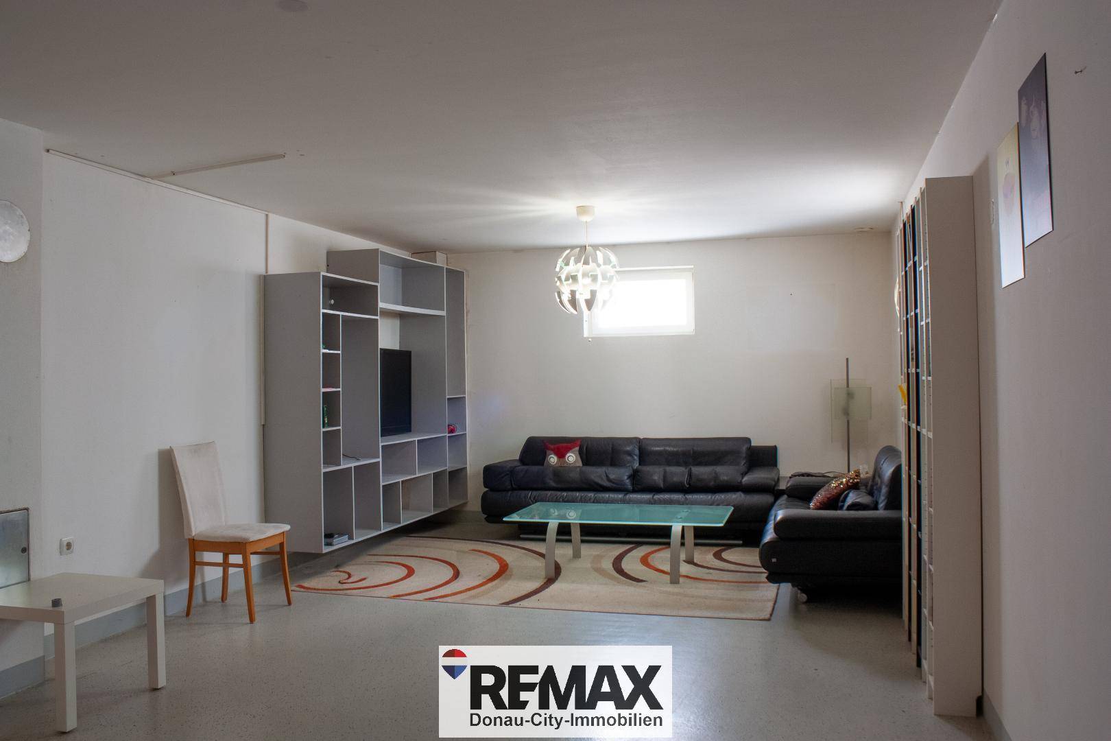 Geräumiges Wohnzimmer im Untergeschoss mit bequemen Sofas und Regalsystemen.