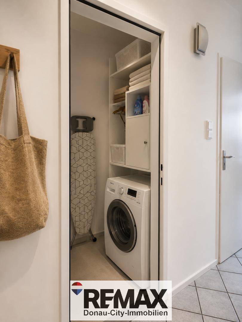 Praktischer Hauswirtschaftsraum mit Waschmaschine, Bügelbrett und Regalen für Stauraum.