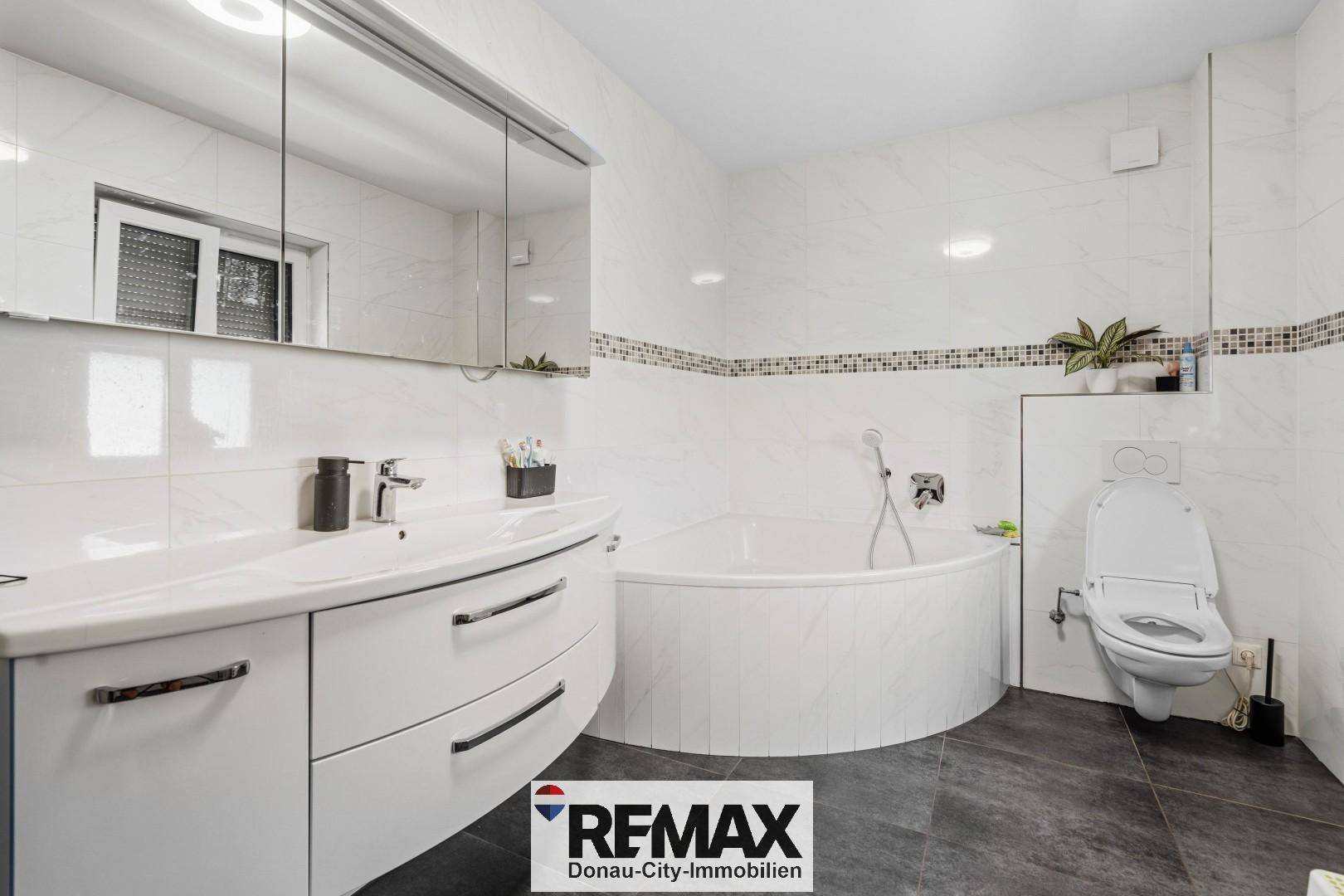 Modernes Badezimmer mit Badewanne, Einzelwaschbecken und Spiegelschrank.