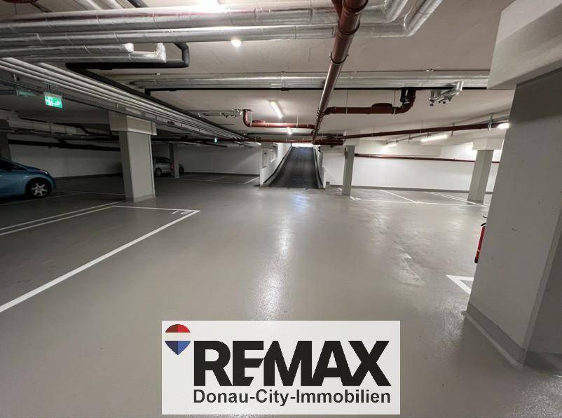 Helle Tiefgarage mit Zufahrtsrampe, Betonwänden und Deckeninstallationen für ein modernes Gebäude.