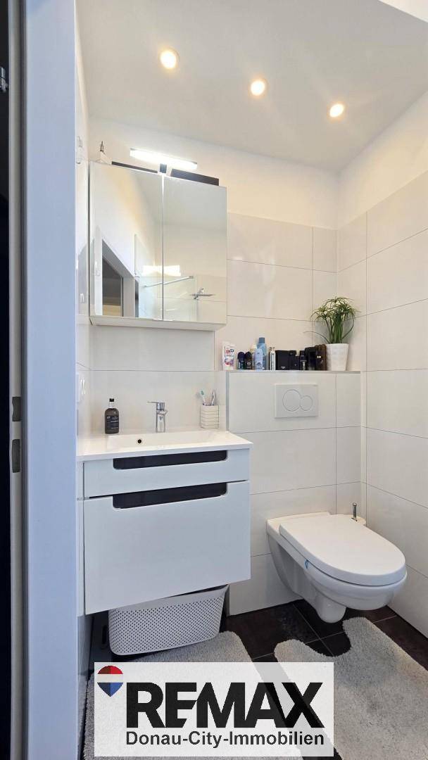 Modernes Badezimmer mit Waschtischunterschrank, Spiegelschrank und wandhängendem WC.