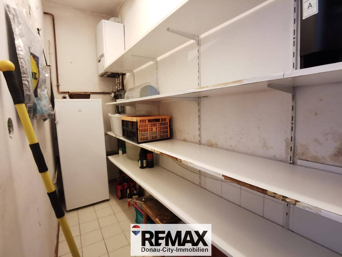 Abstellraum mit vielen Regalen, einem Kühlschrank und einem Heizkessel.