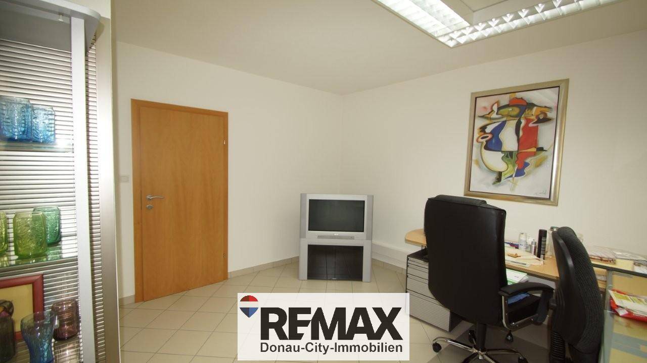 Funktional eingerichtetes Büro mit Schreibtisch, Bürostuhl und Fliesenboden.