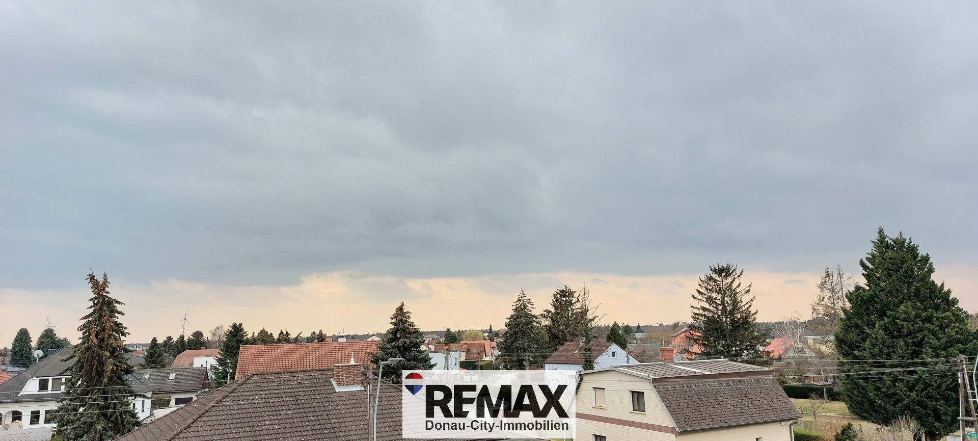 Weitblick über Dächer und Bäume unter bewölktem Himmel, ruhige Umgebung.