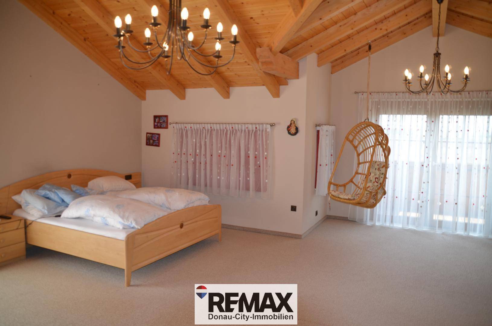 Gemütliches Schlafzimmer mit Holzbalkendecke, Teppichboden und einem bequemen Doppelbett.