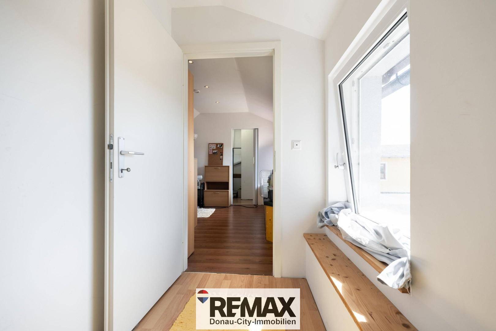 Heller Dachgeschossflur mit Fenster und Holzsitzbank, die zum Verweilen einlädt.