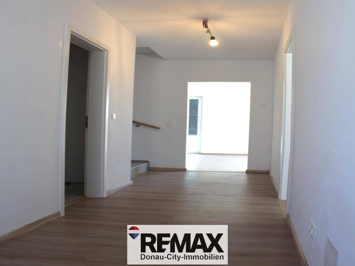Geräumiger Flur mit Laminatboden und Zugang zu weiteren Räumen sowie zur Treppe.