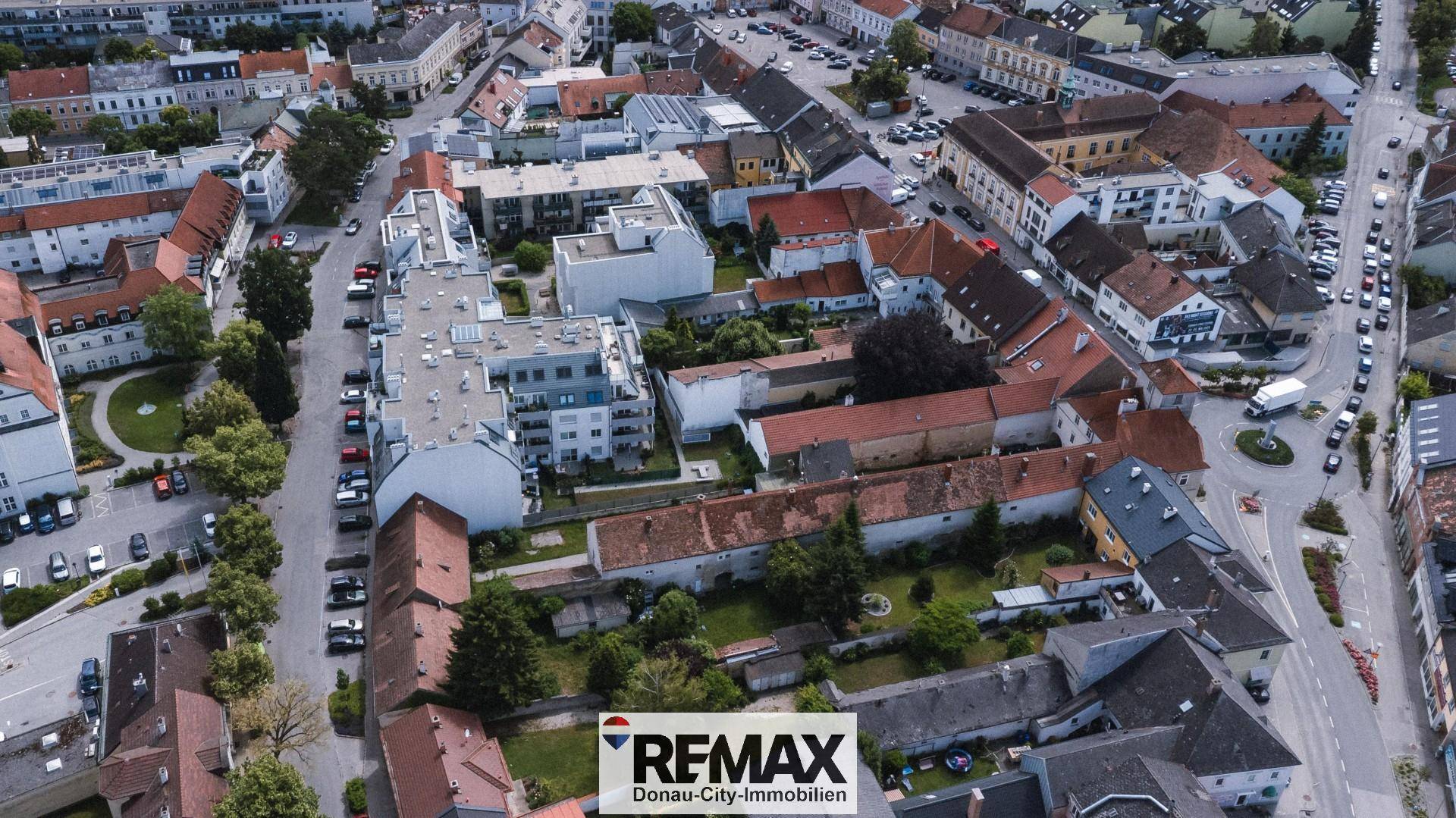 Luftaufnahme der städtischen Umgebung mit Wohngebäuden, Straßen und grünen Flächen.