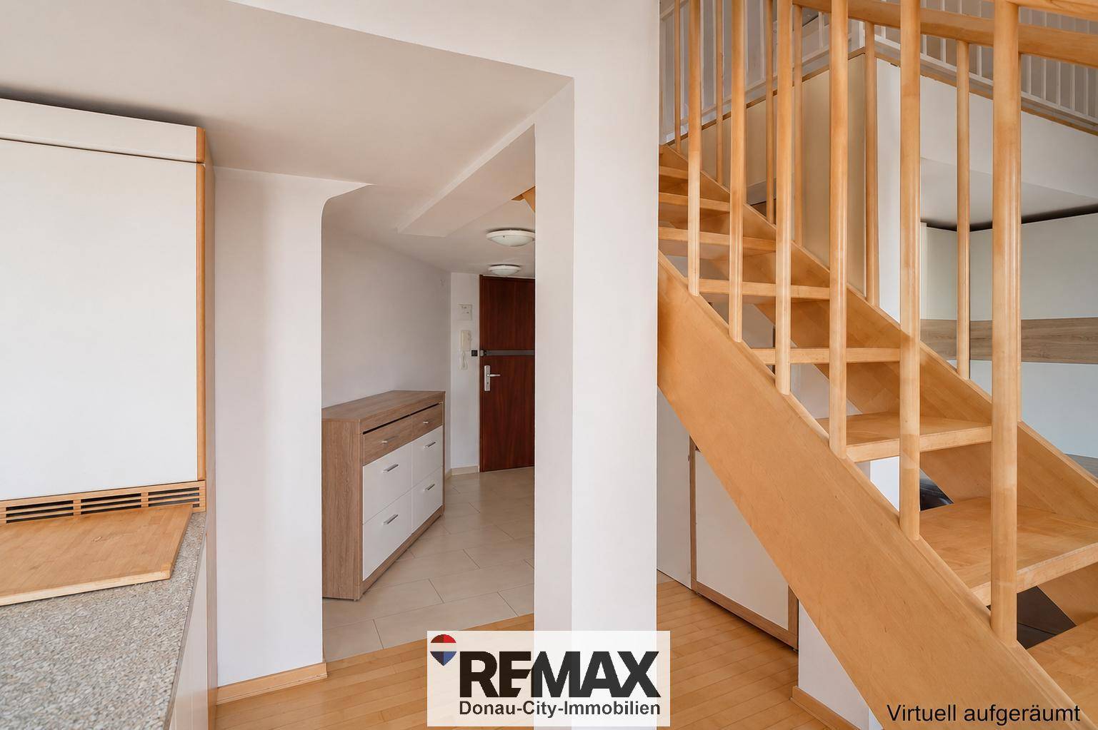 Heller Eingangsbereich mit Holztreppe und Kommode, die zu weiteren Räumen führt.