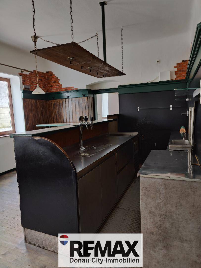 Bar mit Zapfanlage, Edelstahltheke und rustikalen Holzelementen an den Wänden.