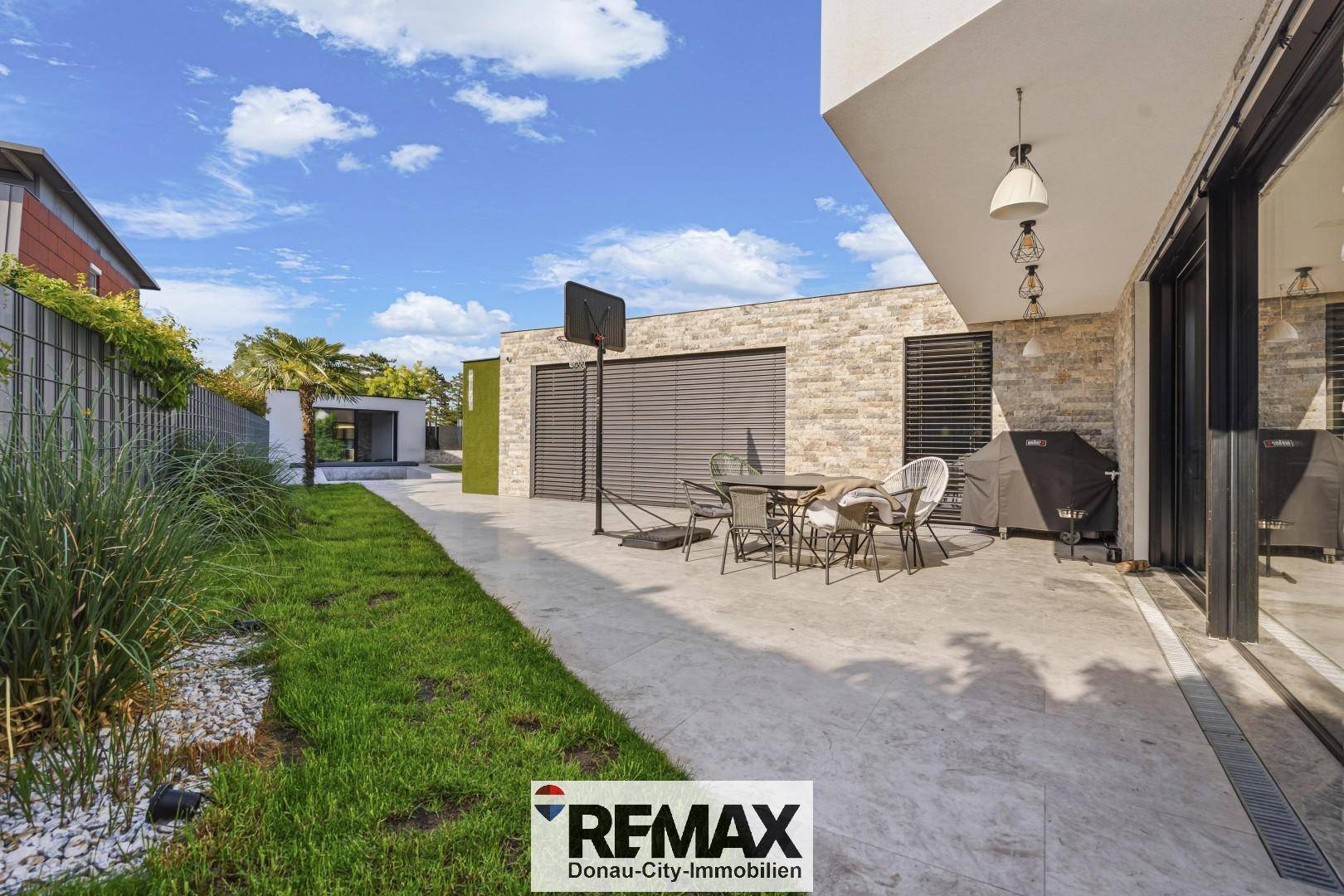 Große Terrasse mit Gartenmöbeln, Grillbereich und Zugang zum Garten.