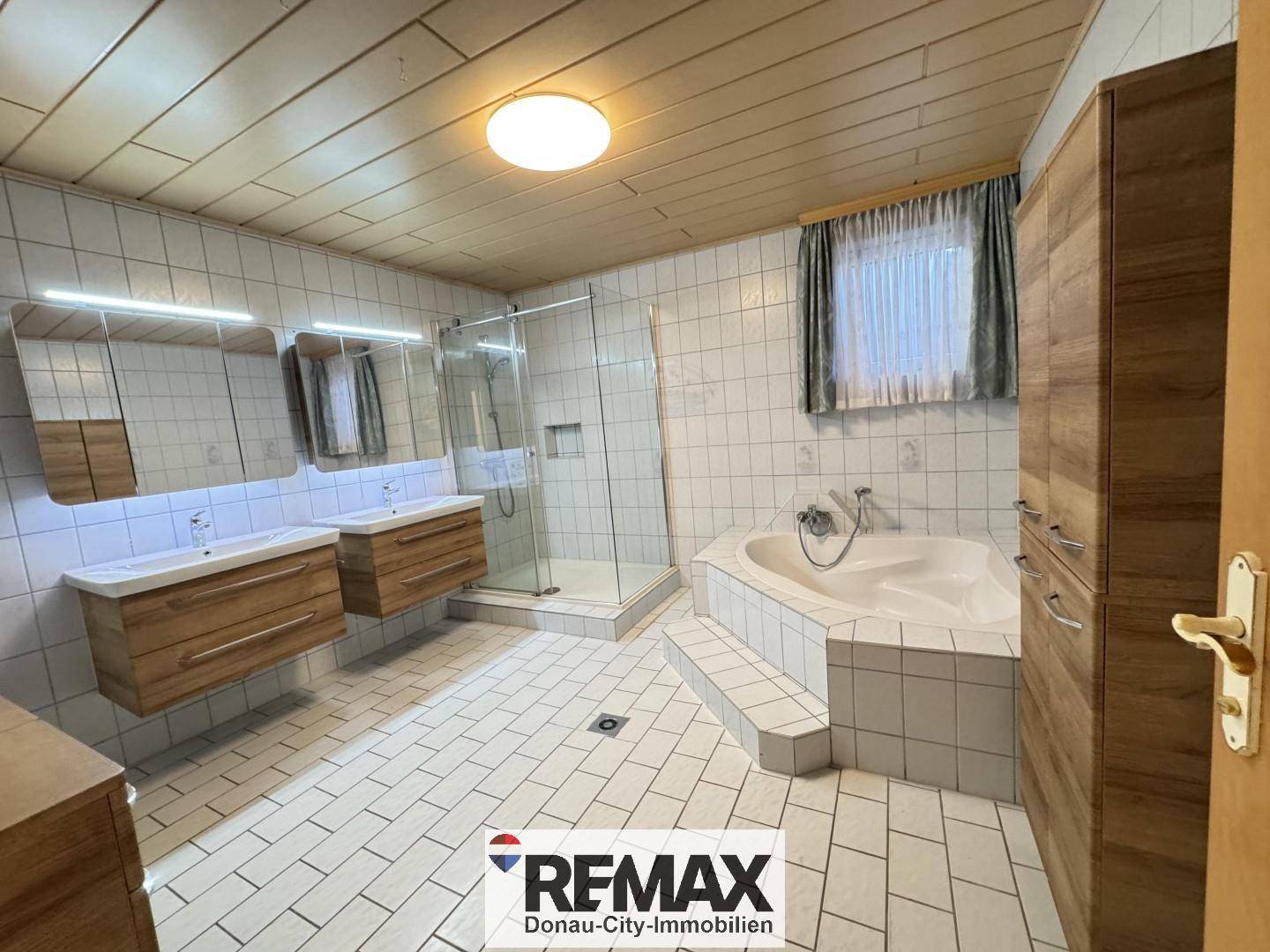 Geräumiges Badezimmer mit Doppelwaschbecken, großer Dusche und einer komfortablen Eckbadewanne.
