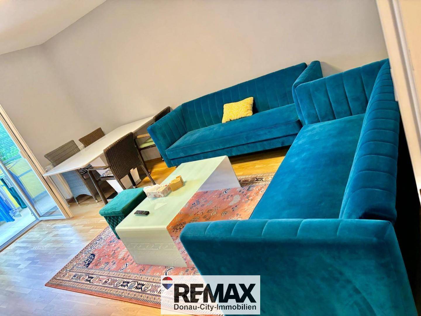 Geräumiger Wohn-Essbereich mit auffälligen blauen Sofas und Holzboden.
