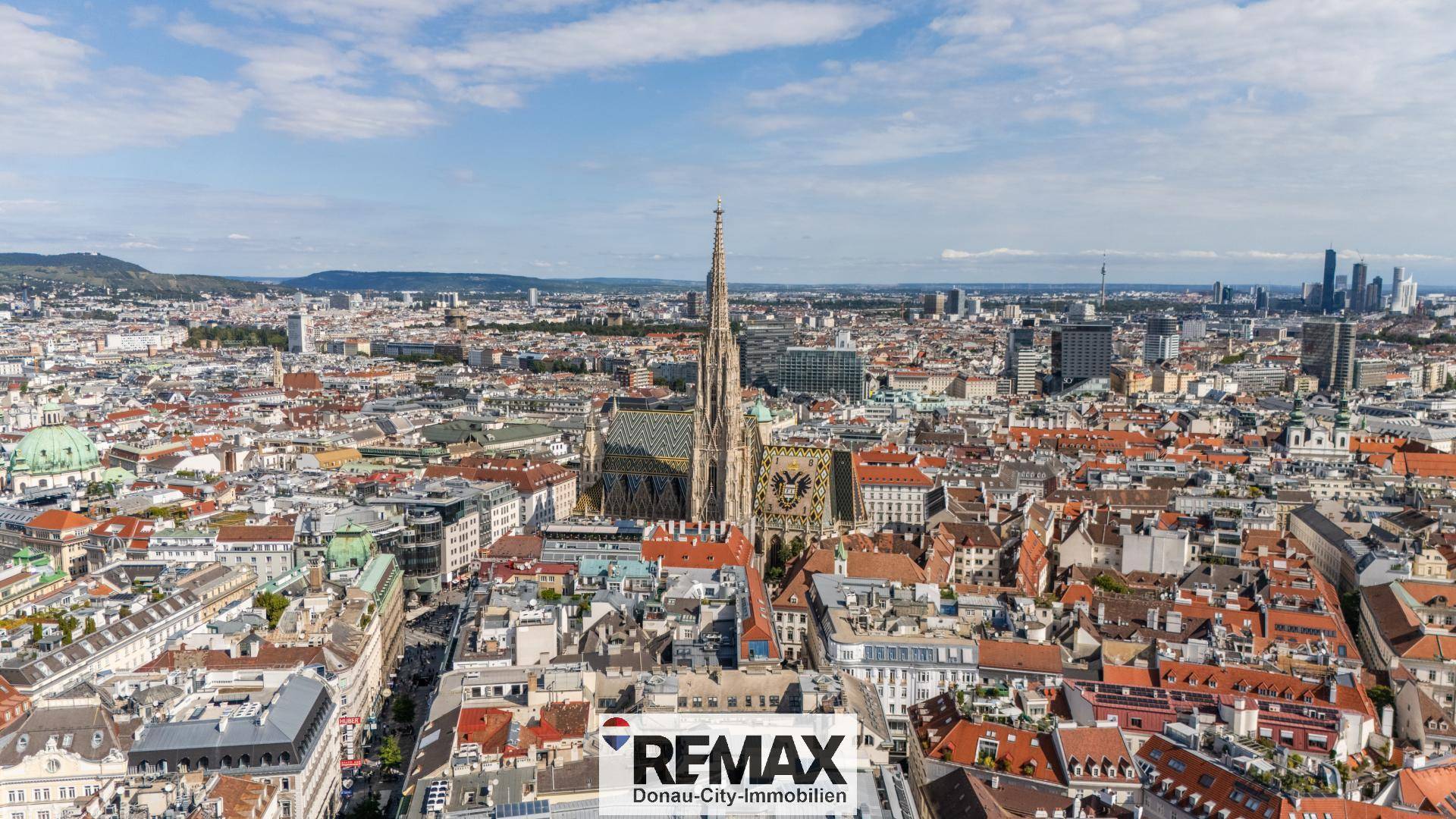 Panoramablick über die historische Stadt Wien mit dem Stephansdom im Zentrum unter blauem Himmel.