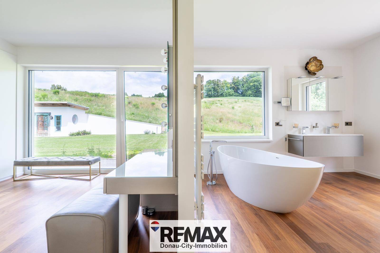 Helles Badezimmer mit freistehender Badewanne und großzügigen Fenstern mit Blick ins Grüne.