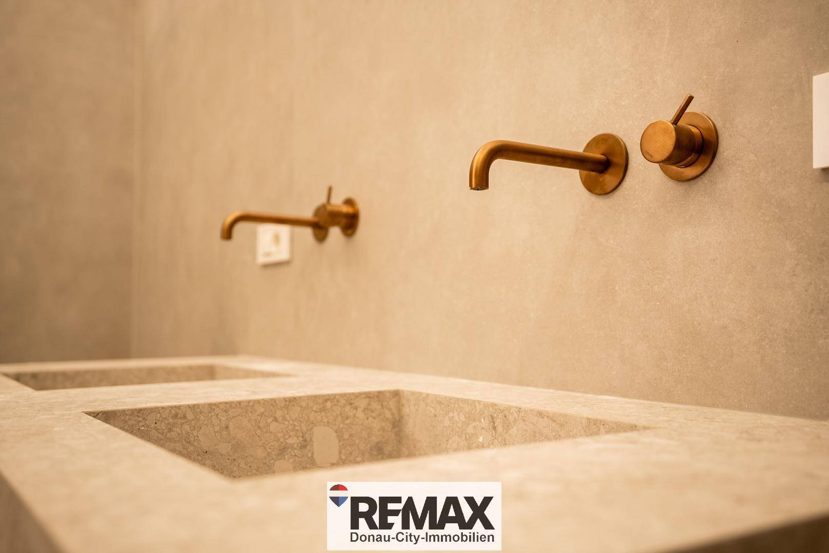 Detailaufnahme eines modernen Doppelwaschbeckens mit eleganten Armaturen in Bronze.
