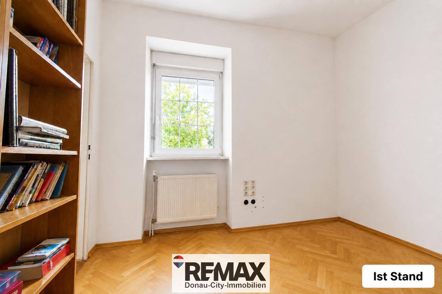 Helles Arbeitszimmer mit Parkettboden und Bücherregal, unmöbliert und funktional.