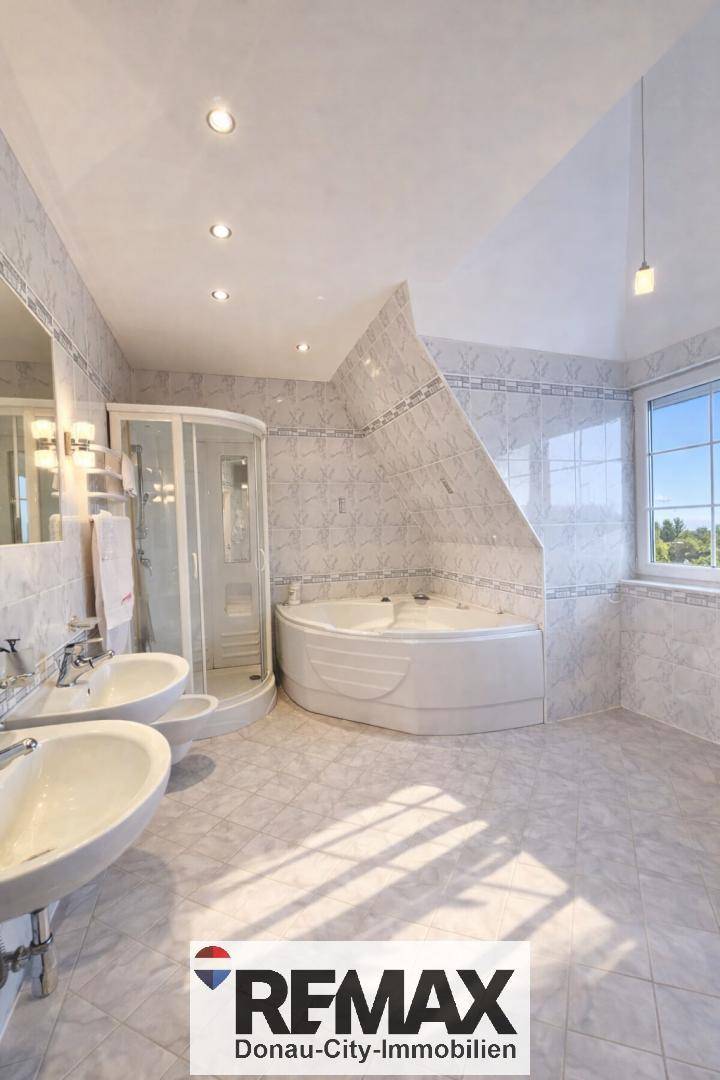 Geräumiges Badezimmer mit Eckbadewanne, Duschkabine, Doppelwaschbecken und Fenster.