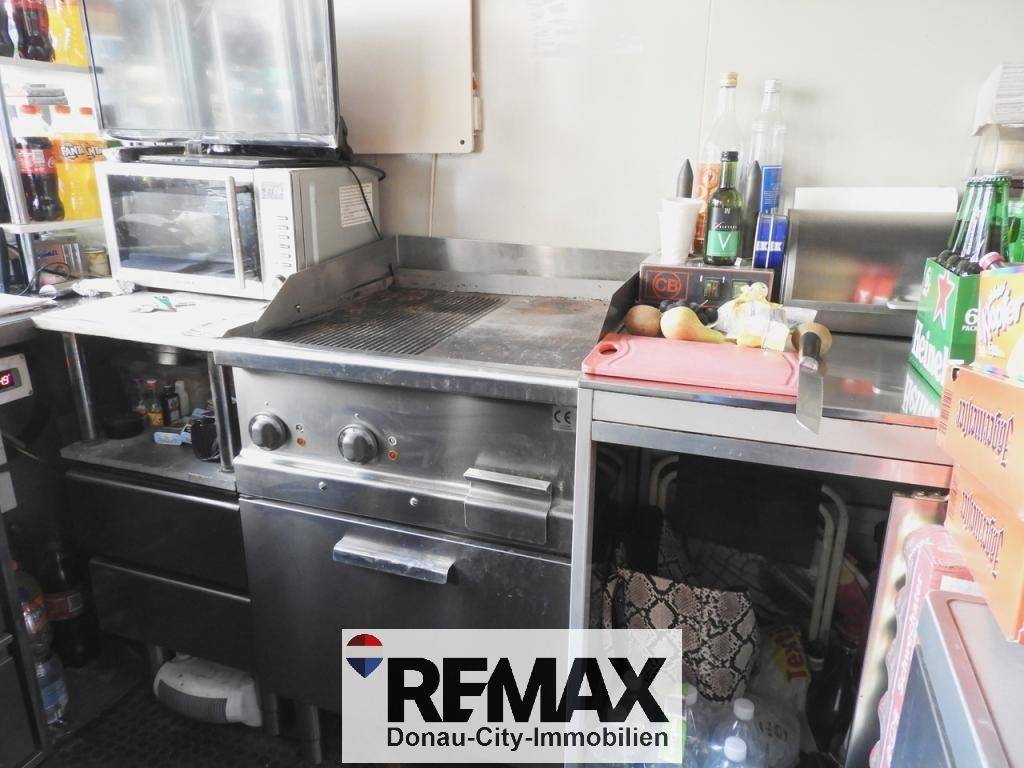 Professionelle Gewerbeküche mit großem Edelstahl-Grill und Mikrowelle, bereit für die Zubereitung von Speisen.