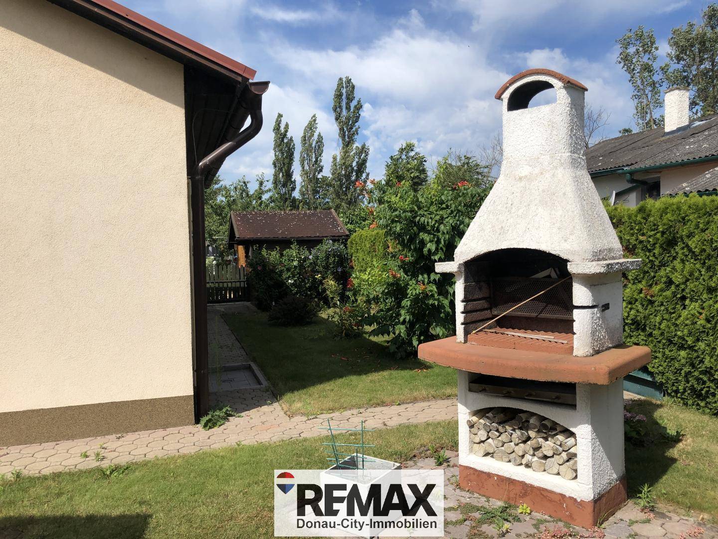 Gemauerter Grillplatz im Garten mit integriertem Stauraum für Brennholz.
