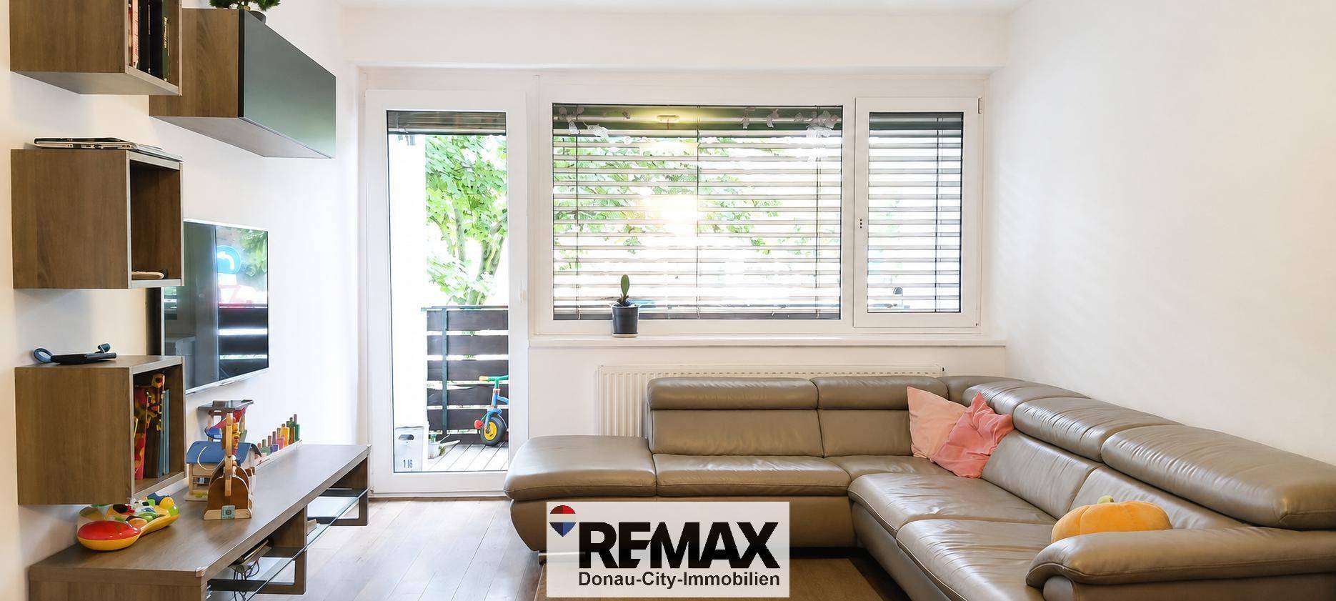 Gemütliches Wohnzimmer mit großem Ecksofa, Holzfußboden und Zugang zu einem Außenbereich.