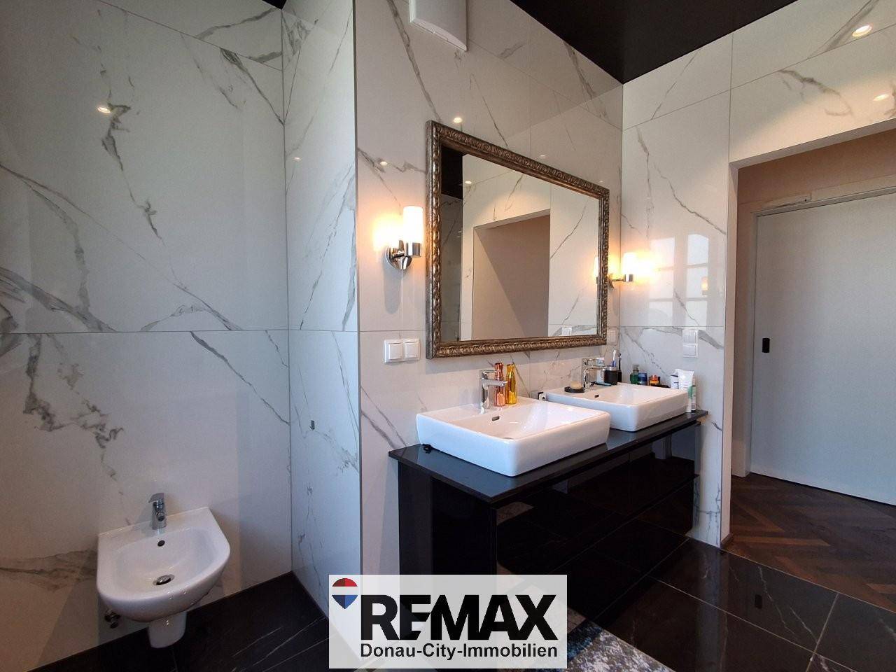Luxuriöses Badezimmer mit Marmorfliesen, Doppelwaschbecken und Bidet.