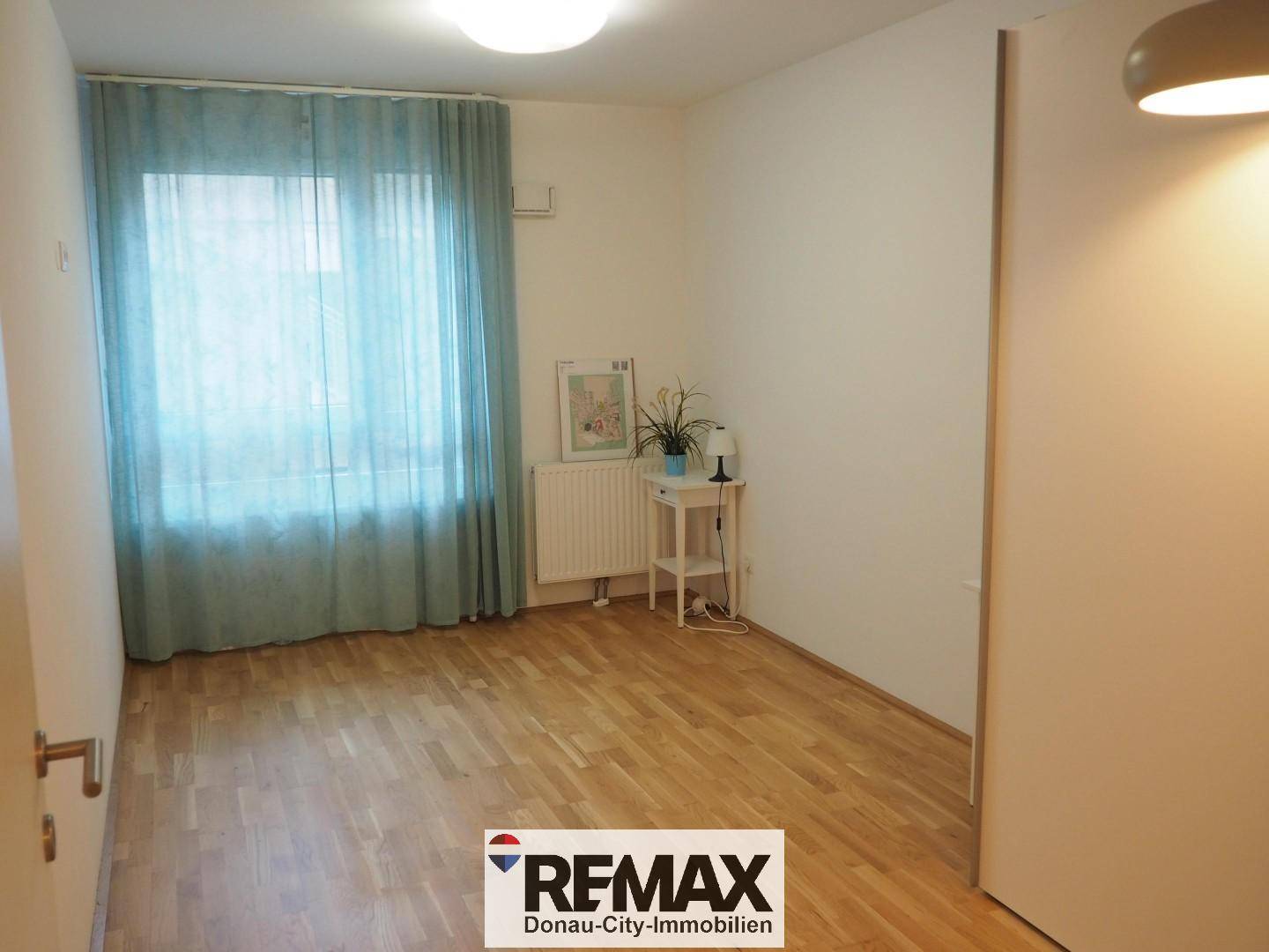 Helles Schlafzimmer mit Parkettboden und großem Fenster, bereit zur individuellen Gestaltung.