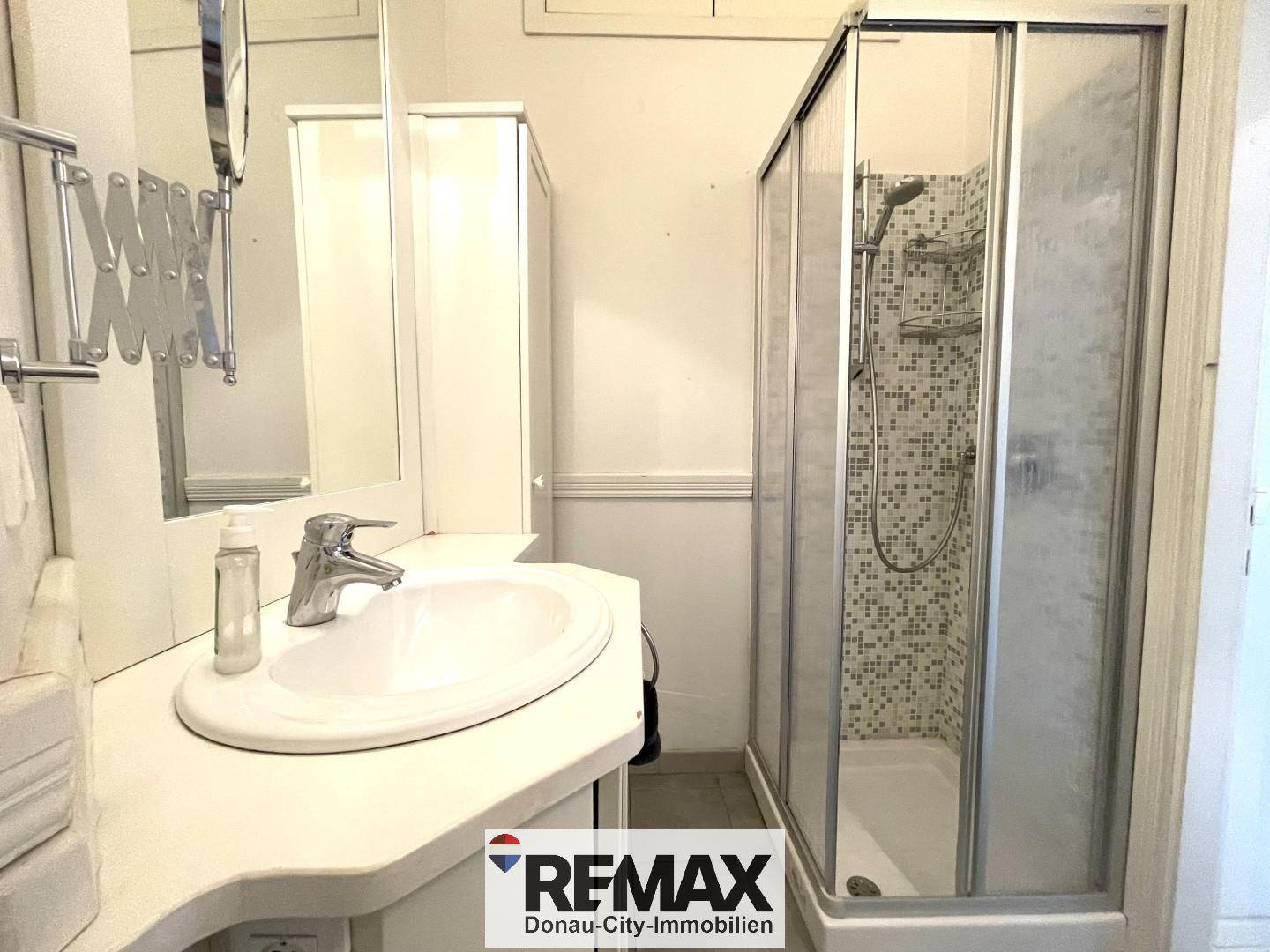 Funktionales Badezimmer mit Duschkabine, Einzelwaschbecken und Spiegelschrank.