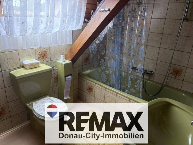 Badezimmer im Dachgeschoss mit grünen Fliesen, Badewanne und WC.