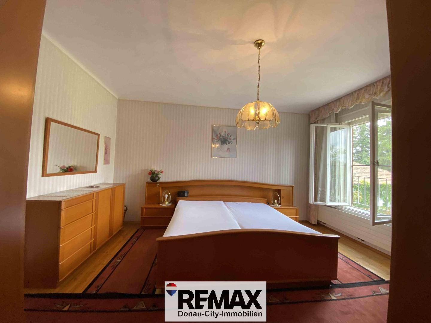 Schlafzimmer mit Doppelbett, Holzmöbeln und Fenster mit Blick ins Grüne.