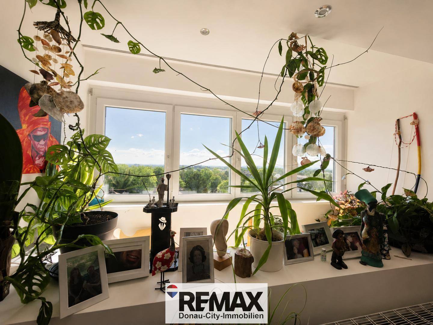 Fensterbank mit zahlreichen Pflanzen und Dekorationen, die einen weiten Ausblick bieten.
