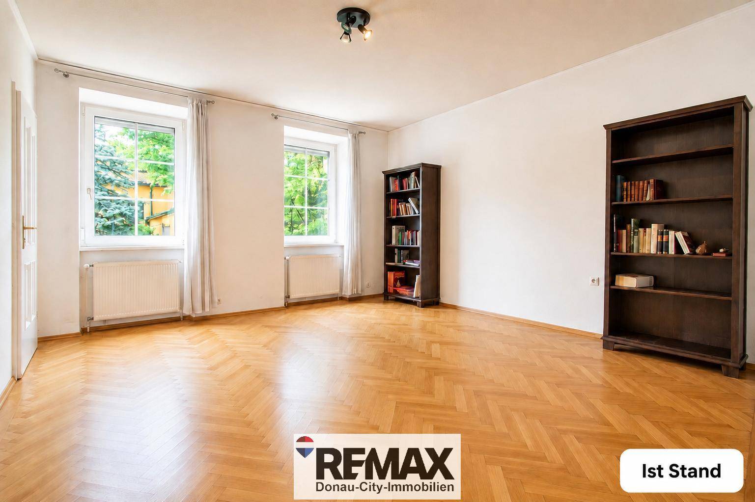 Großes Arbeitszimmer mit Parkettboden und zwei Fenstern, unmöbliert und hell.