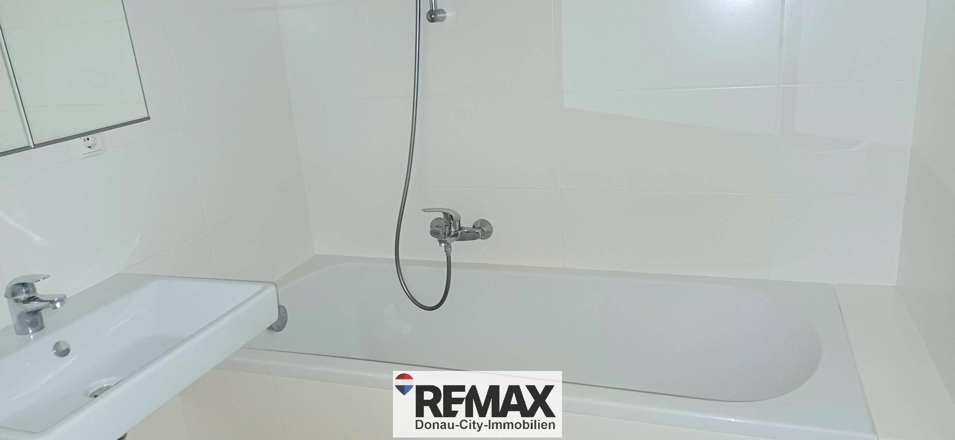 Badezimmer mit Badewanne, Duscharmatur und einem einzelnen Waschbecken.