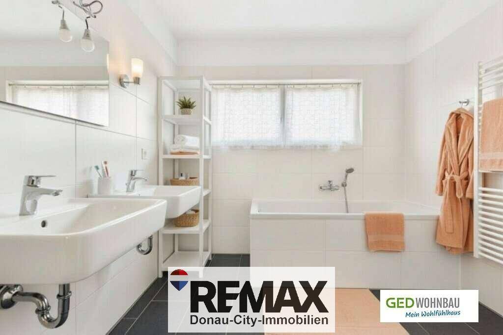 Modernes Badezimmer mit Doppelwaschbecken, Badewanne und beheiztem Handtuchhalter für Komfort.