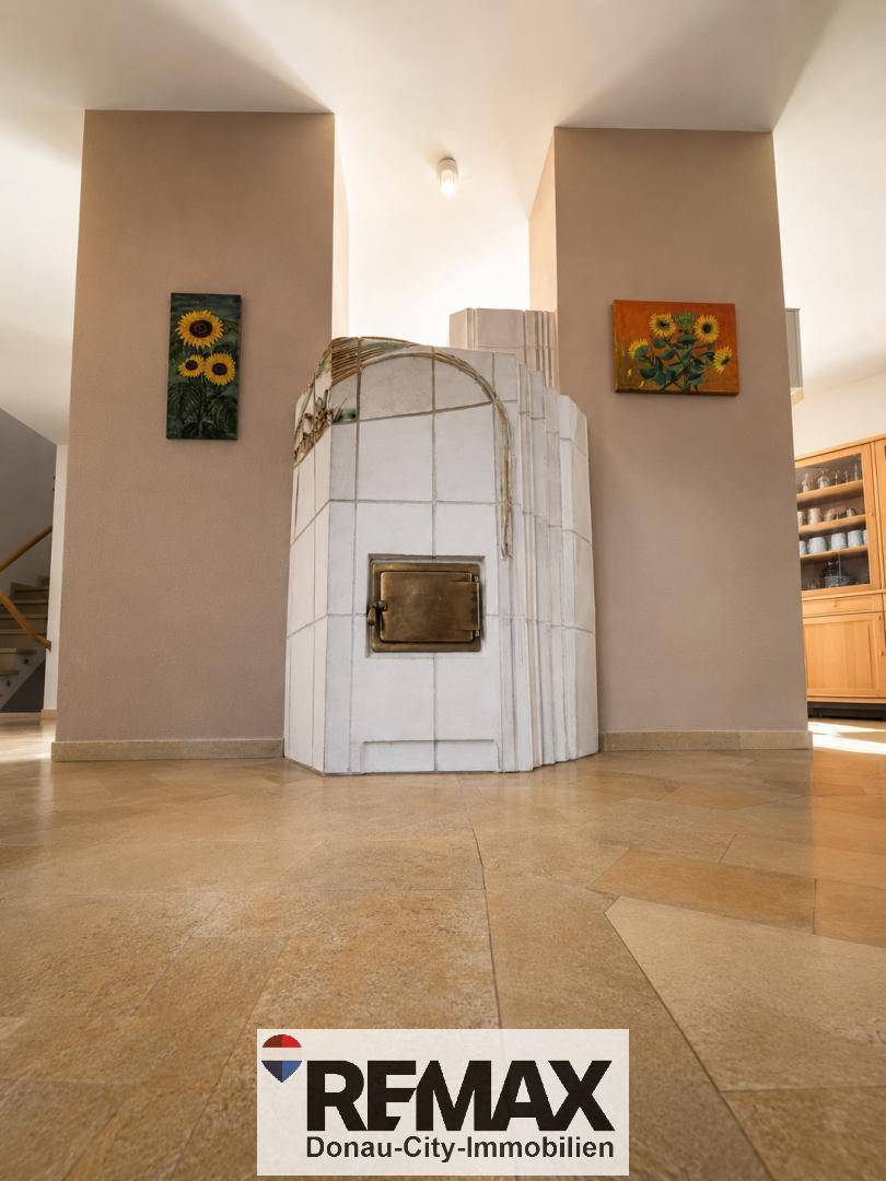 Traditioneller Kachelofen als zentrales Heizelement in einem hellen Wohnbereich mit Fliesenboden.