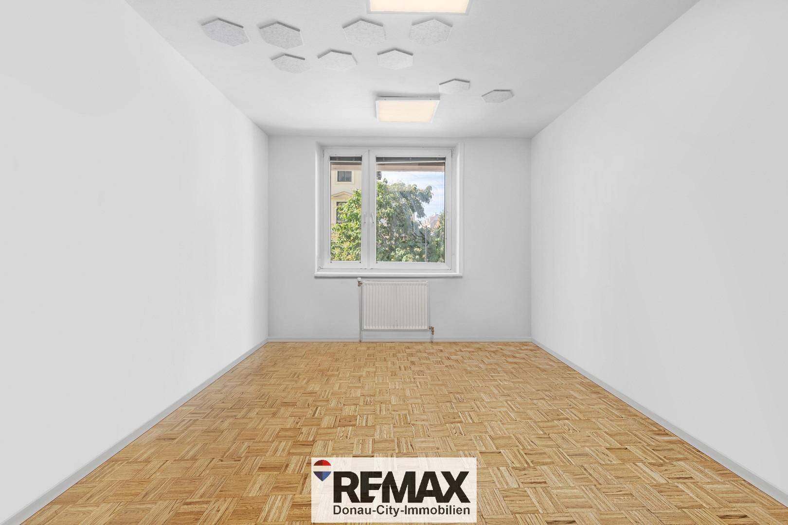 Leerer Raum mit Parkettboden, weißen Wänden und einem Fenster, ergänzt durch dekorative Deckenpaneele.