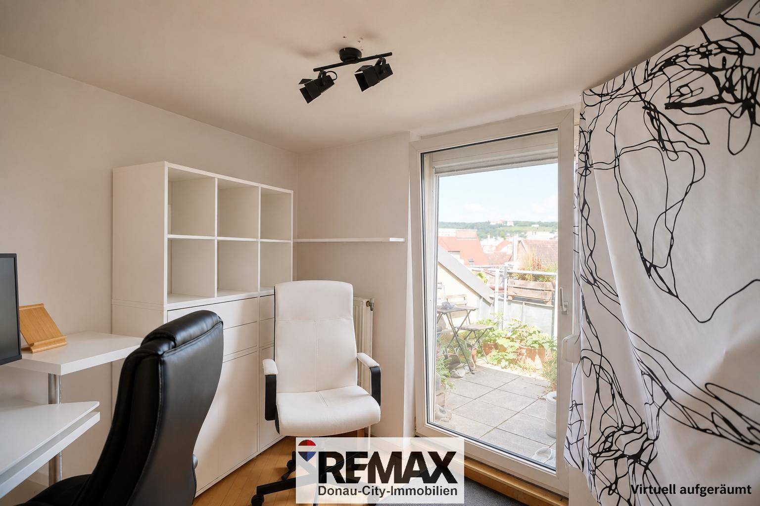 Heller Arbeitsbereich mit Schreibtisch und Zugang zu einer Außenterrasse durch eine große Fenstertür.